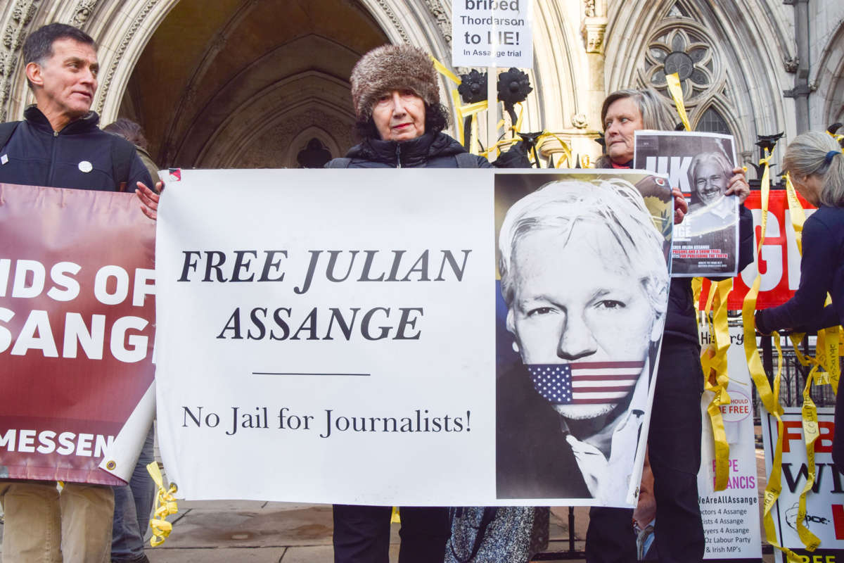 An English protester holds a sign showing Julian Assange gagged with a U.S. flag