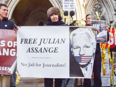 An English protester holds a sign showing Julian Assange gagged with a U.S. flag