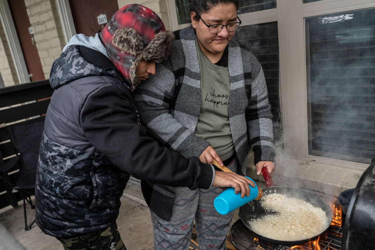 Two people cook rice on an outdoor grill