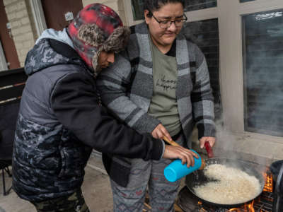 Two people cook rice on an outdoor grill