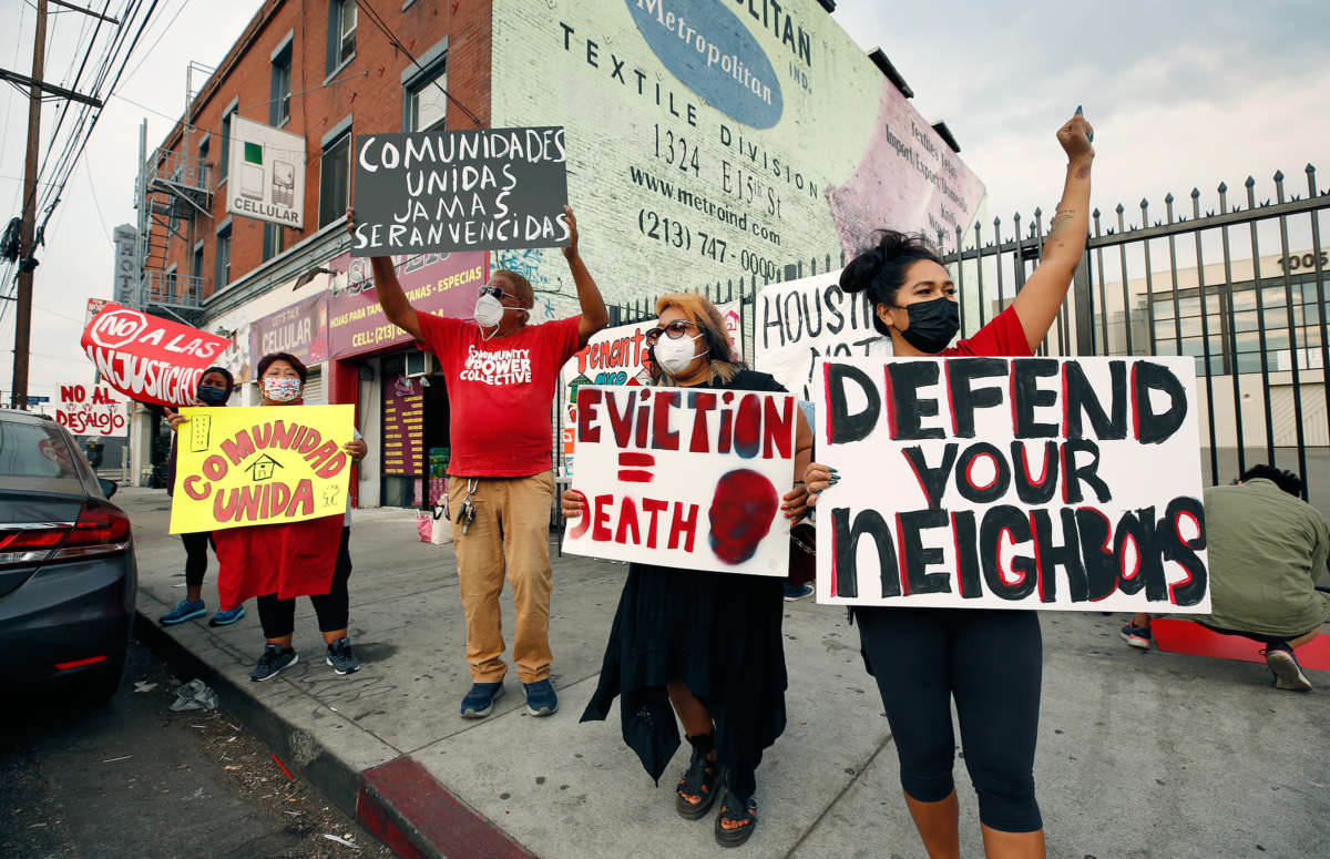 People raise their fists and display signs denouncing eviction in the midst of a pandemic