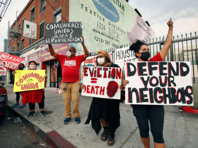 People raise their fists and display signs denouncing eviction in the midst of a pandemic
