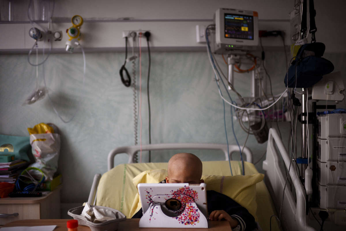 A small child looks at a tablet screen while in a hospital