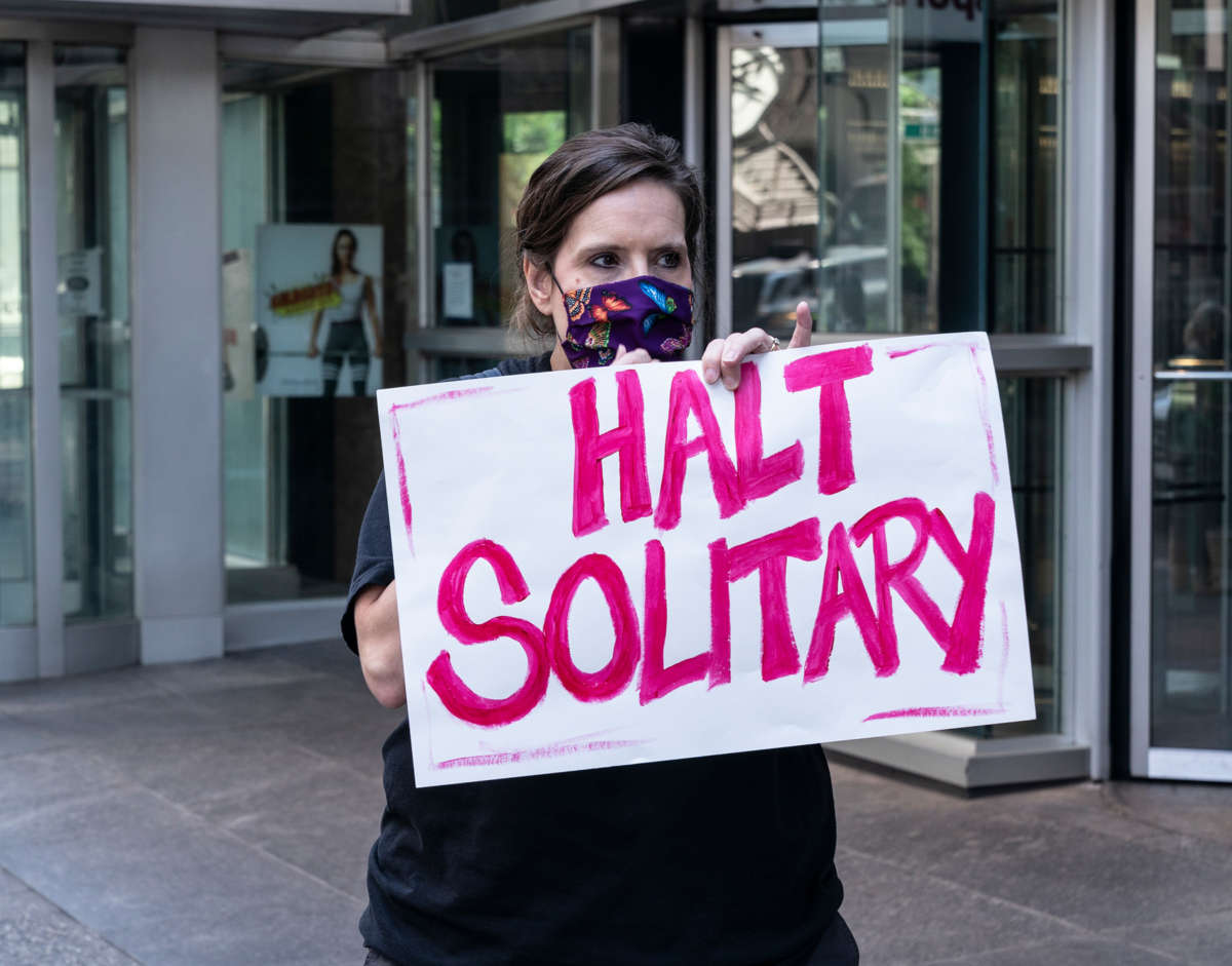 An activist holds a sign reading "HALT SOLITARY"