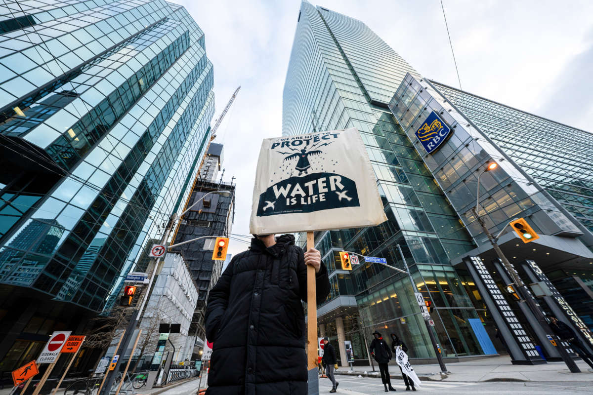 An activist holds up a placard saying, "We Are Here to Protect, Water is Life" during the demonstration. Protesters gather in solidarity with Wetísuwetíen Land Defenders in Toronto, Canada, on December 21, 2021.
