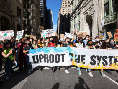 Climate change protesters march in New York City with banner reading Uproot the System