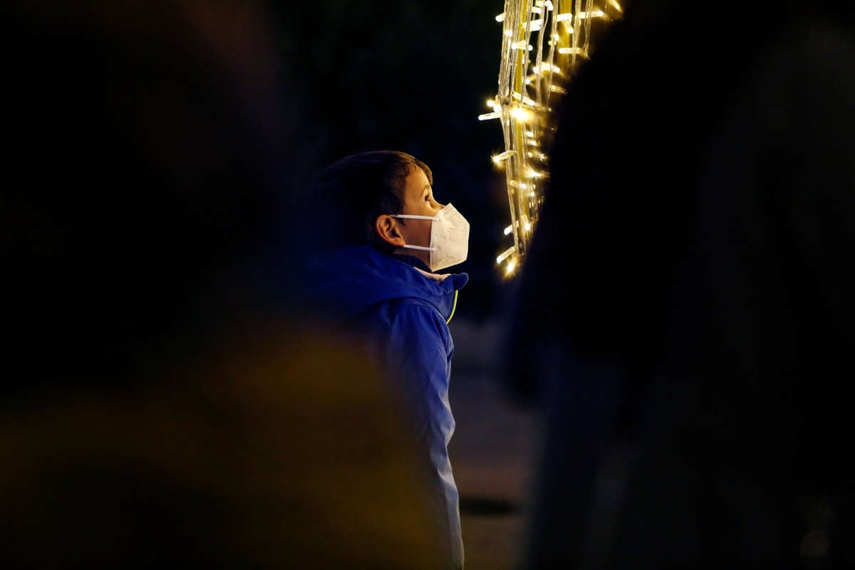 A boy with a face mask looks the Christmas lights during the winter in Granada, Spain, amid the coronavirus pandemic on December 20, 2021.