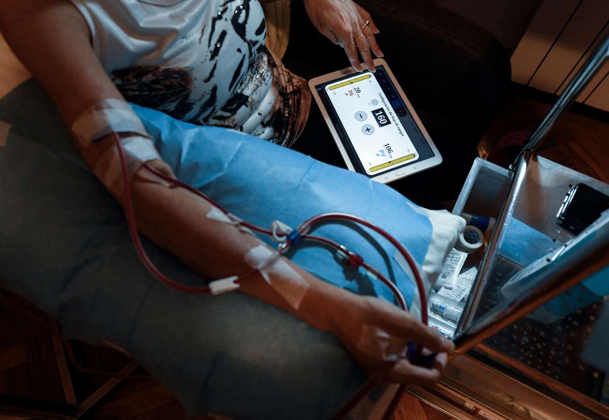 A dialysis patient looks at the tablet on their lap