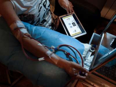 A dialysis patient looks at the tablet on their lap