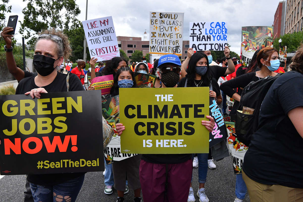 A person holds a sign reading "THE CLIMATE CRISIS IS HERE" during an outdoor protest