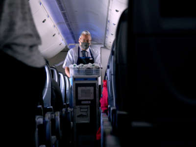 A masked flight attendant passes out refreshments on a flight from San Francisco, California, to Newark, New Jersey, on October 27, 2020.