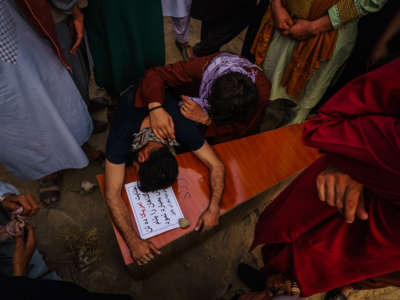 A relative weeping over the casket of a child killed by U.S. air strikes in Afghanistan