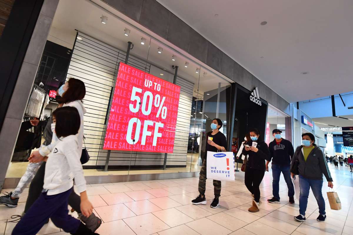 People walk stores offering sales at a shopping mall in Santa Anita, California, on December 20, 2021.