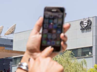 An Israeli citizen uses their iPhone in front of the building housing the Israeli NSO group, on August 28, 2016, in Herzliya, near Tel Aviv.