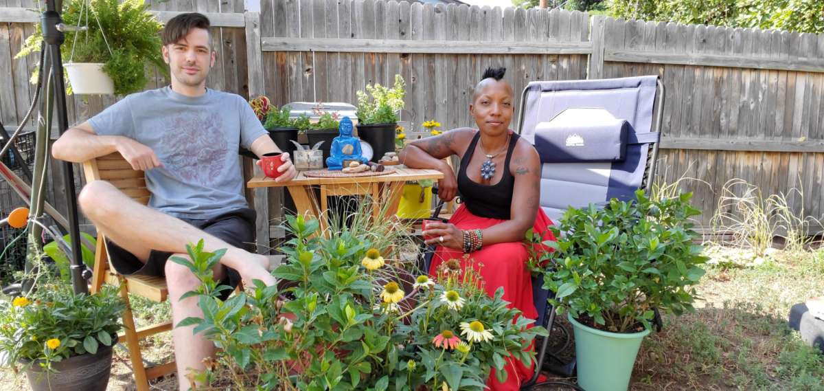 Two people sit in an outdoor garden, one white and the other Black