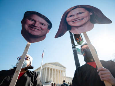 Protesters display cardboard cutouts of Justices Brett Kavanaugh and Amy Coney Barrett's faces