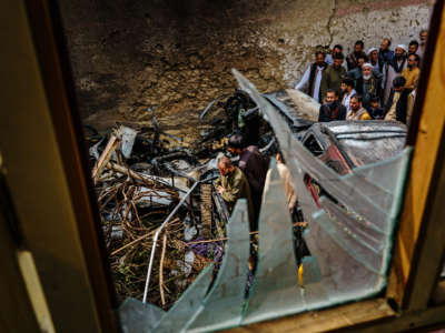 Relatives and neighbors of the Ahmadi family gather around the incinerated husk of a vehicle targeted and hit by an American drone strike that killed 10 civilians including 7 children, in Kabul, Afghanistan, on August 30, 2021.