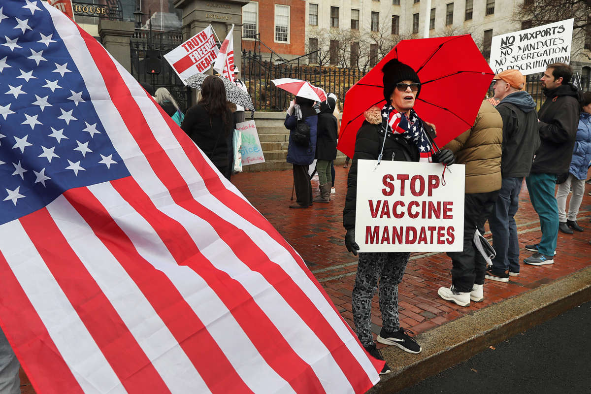 A protester wears a sign that reads Stop Vaccine Mandates during a demonstration in front of the State House on Beacon Street in Boston on January 5, 2022.