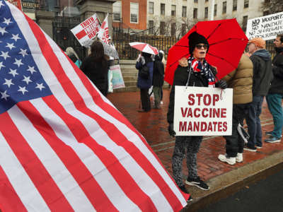 A protester wears a sign that reads Stop Vaccine Mandates during a demonstration in front of the State House on Beacon Street in Boston on January 5, 2022.