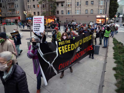 On the one year anniversary of the attack on the U.S. Capitol, people march past the Department of Justice as Indivisible SF and Indivisible East Bay hold a vigil and march in San Francisco, California, on January 6, 2022.