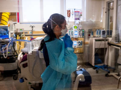 Repertory care practitioner My Pham removes her isolation gown as she exits a room with a COVID-19 patient at Providence St. Jude Medical Center on January 8, 2022, in Fullerton, California.