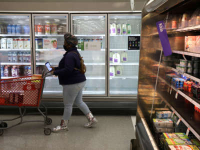 A shopper passes by depleted refrigerated shelves at a Target store on January 12, 2022, in Springfield, Virginia.