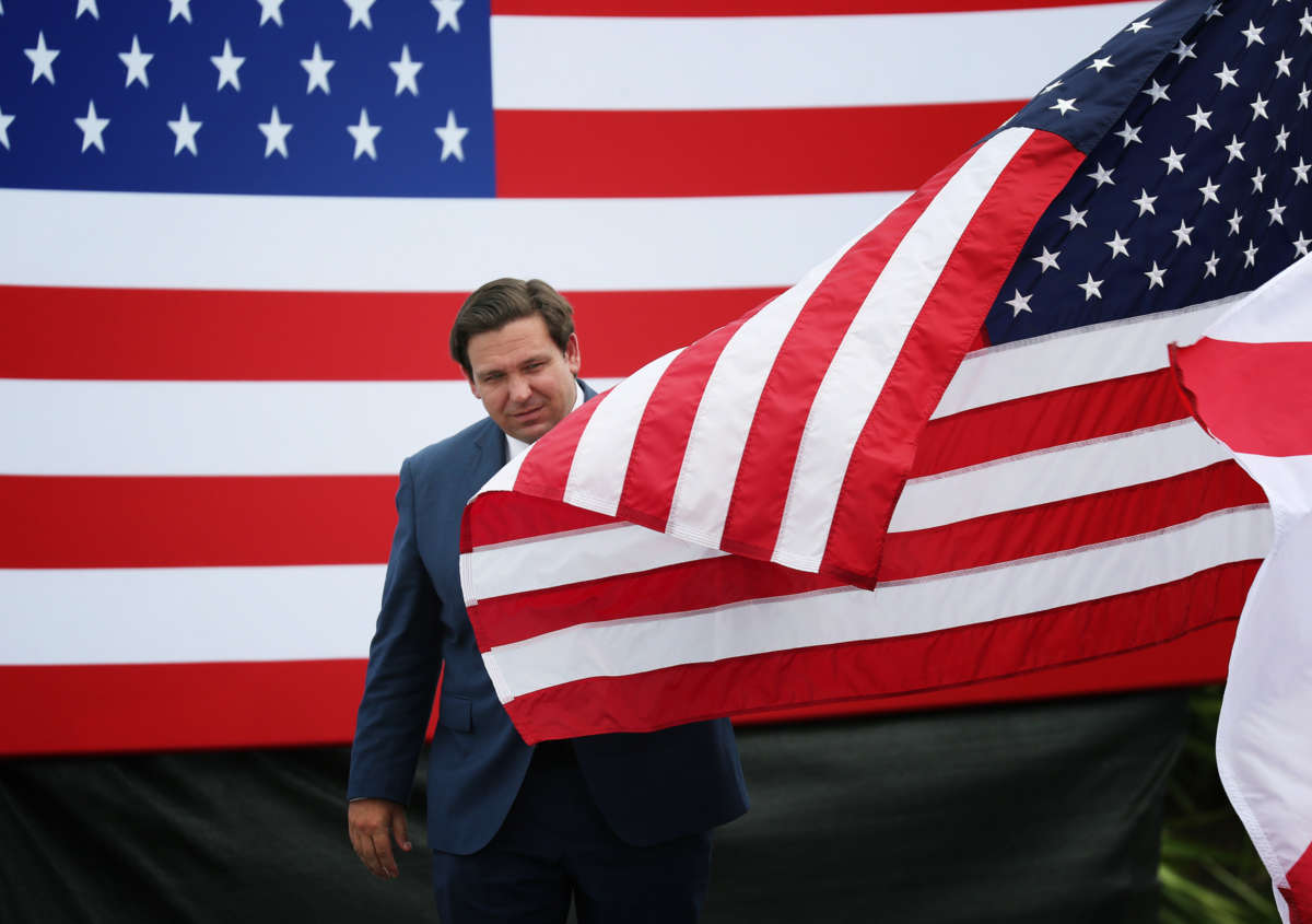 Gov. Ron DeSantis emerges from between to U.S. flags