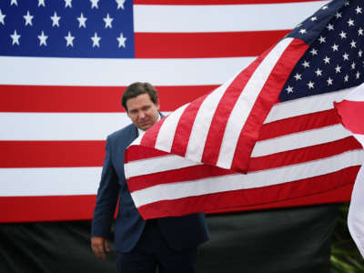 Gov. Ron DeSantis emerges from between to U.S. flags