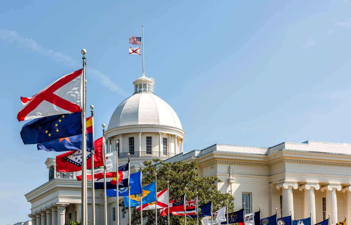 State capitol building in Alabama during sunny day with old historic architecture of government and many row of flags by dome