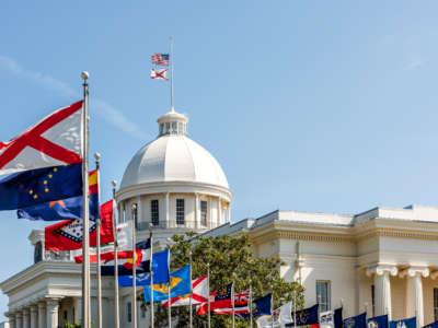 State capitol building in Alabama during sunny day with old historic architecture of government and many row of flags by dome