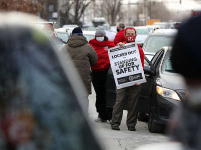Teacher Stuart Abram holds a sign in support of the Chicago Teachers Union on January 5, 2022, the first day that classes were canceled amid the dispute over COVID-19 safety measures.