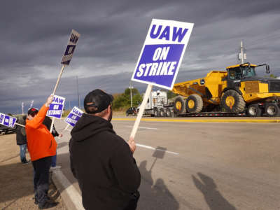 A truck hauls a piece of John Deere equipment from the factory past workers picketing outside of the John Deere Davenport Works facility on October 15, 2021, in Davenport, Iowa.