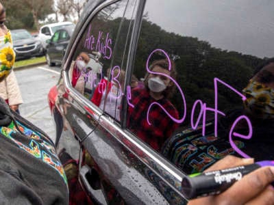 A parent decorates her car while gathering at the Leona Canyon Trailhead before participating in a car caravan demonstration in Oakland, California, on January 7, 2022. Some Oakland Unified teachers called a sickout on that day, saying they don't feel safe teaching. They're calling for two weeks of remote learning during the latest Omicron surge.