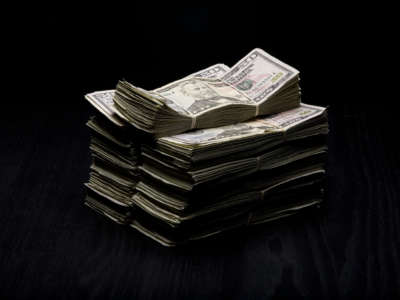 Stacks of $50 Bills on dark wooden table.