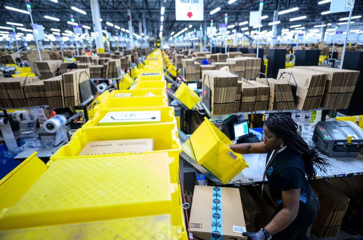 A worker sorts boxes at an amazon fulfillment center