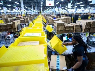 A worker sorts boxes at an amazon fulfillment center