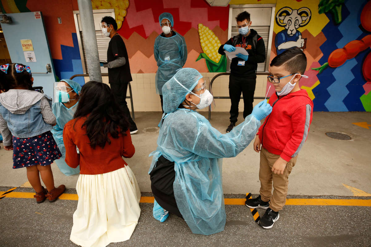 A kindergarten student gets a COVID-19 test from an EMT on the campus of Heliotrope Avenue Elementary School on April 13, 2021, in Maywood, California.