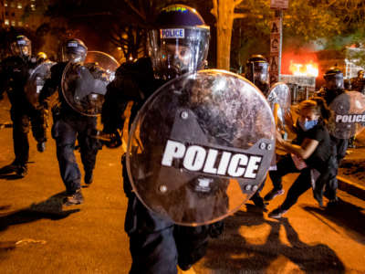 A police officer charges forward as people protest the death of George Floyd at the hands of Minneapolis police in front of the White House in Washington, D.C., on May 31, 2020.