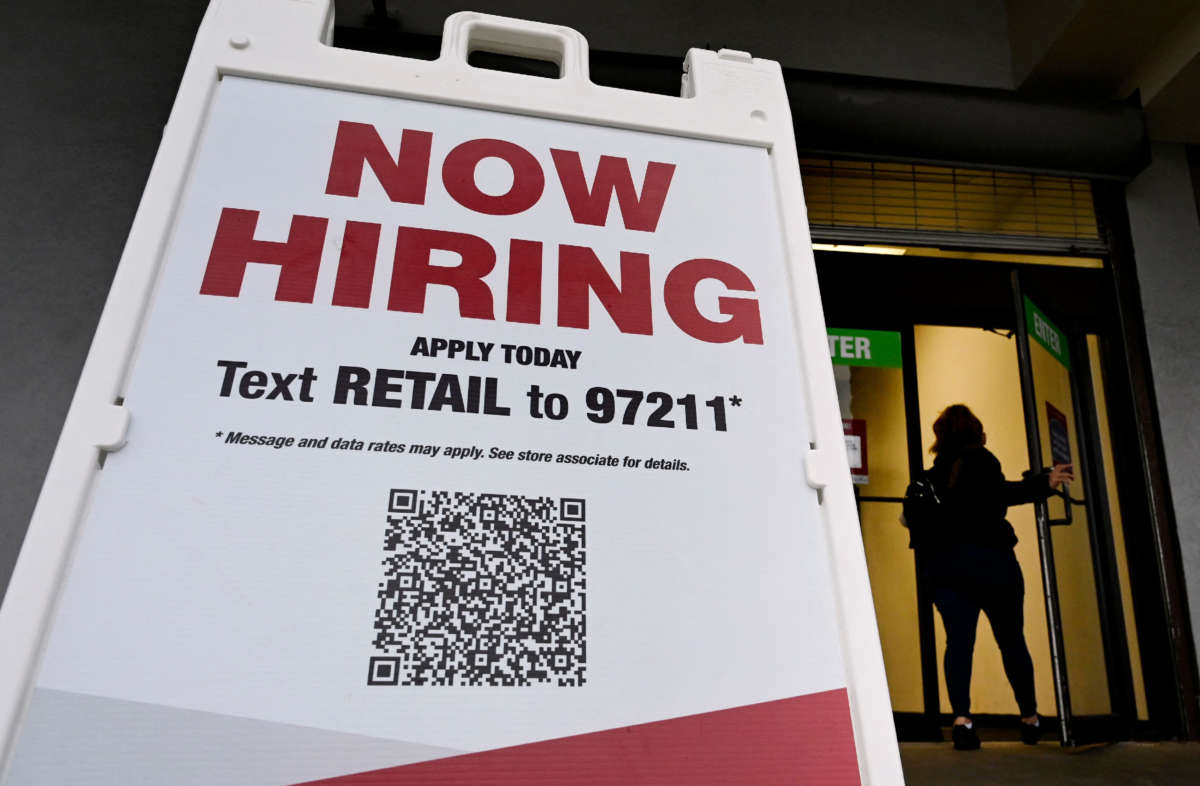 A woman walks past a "Now Hiring" sign in front of a store on January 13, 2022, in Arlington, Virginia.