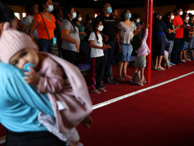 A 7-month-old migrant from Mexico is held by a family member as asylum-seeking migrants wear face coverings at a worship service in the Agape migrant shelter on July 22, 2021 in Tijuana, Mexico.