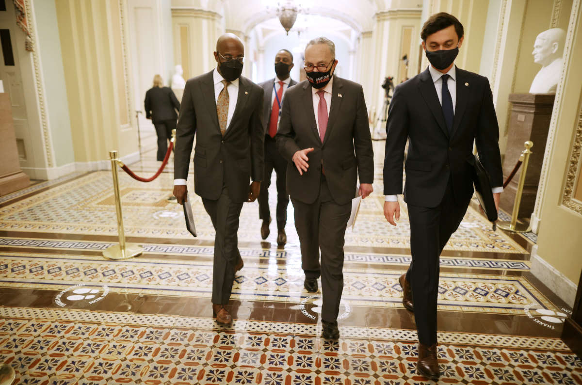 Senate Majority Leader Charles Schumer, center, walks with Sen. Raphael Warnock, left, and Sen. Jon Ossoff, right, on their way to a news conference at the U.S. Capitol on February 11, 2021, in Washington, D.C.
