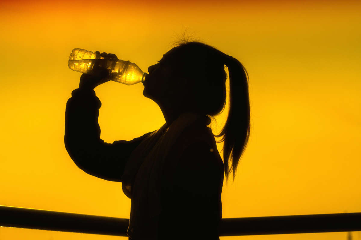 Silhouette of person drinking from water bottle