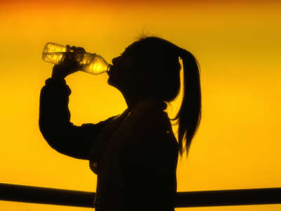 Silhouette of person drinking from water bottle