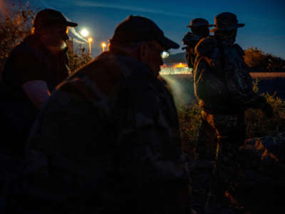 Militia members share cigarettes while patrolling the U.S.-Mexico border in Sunland Park, New Mexico, on March 20, 2019.