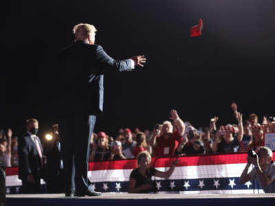 Former President Donald Trump tosses a "Make America Great Again" hat to his supporters as he takes the stage during a "Save America" rally at York Family Farms on August 21, 2021, in Cullman, Alabama.