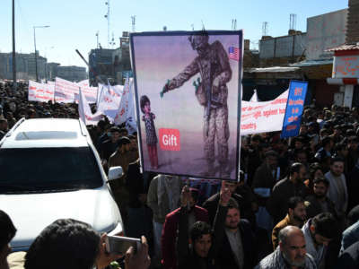 People hold placards as they march during a protest against the recent remarks by President Joe Biden to freeze Afghanistan's assets, in Kabul on February 15, 2022.