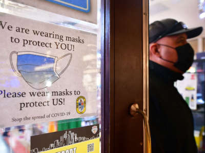 A man walks past a sign posted on a storefront reminding people to wear masks, on February 25, 2022, in Los Angeles, California.