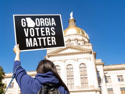 Demonstrators stand outside of the Georgia Capitol building, to oppose a bill that will add voting restrictions to the state's upcoming elections on March 3, 2021, in Atlanta, Georgia.