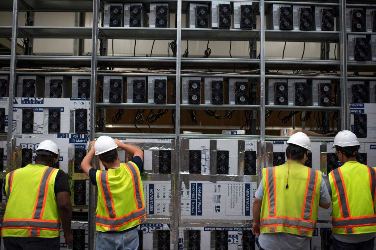 Workers install a new row of Bitcoin mining machines at the Whinstone U.S. Bitcoin mining facility in Rockdale, Texas, on October 9, 2021.