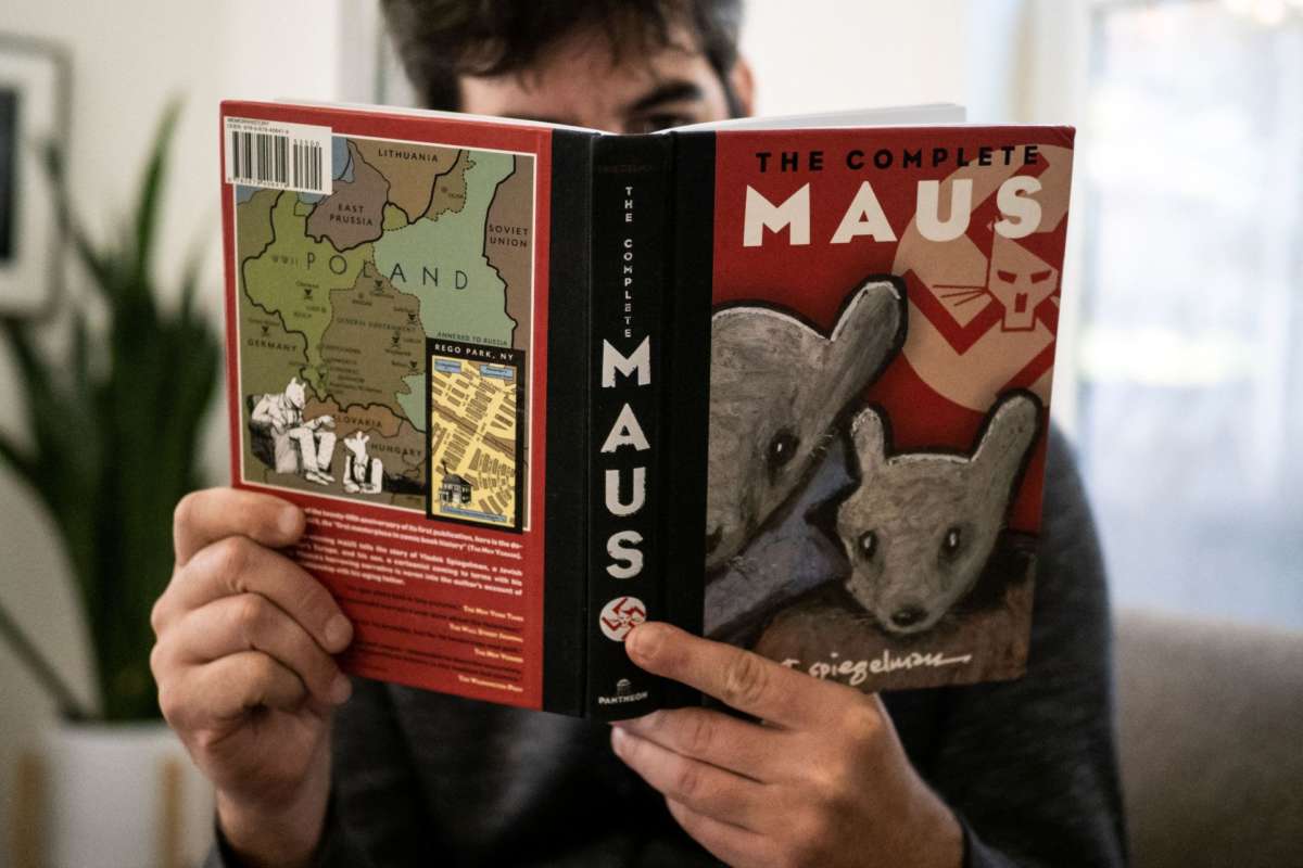 A person holds open a copy of the graphic novel, "Maus"